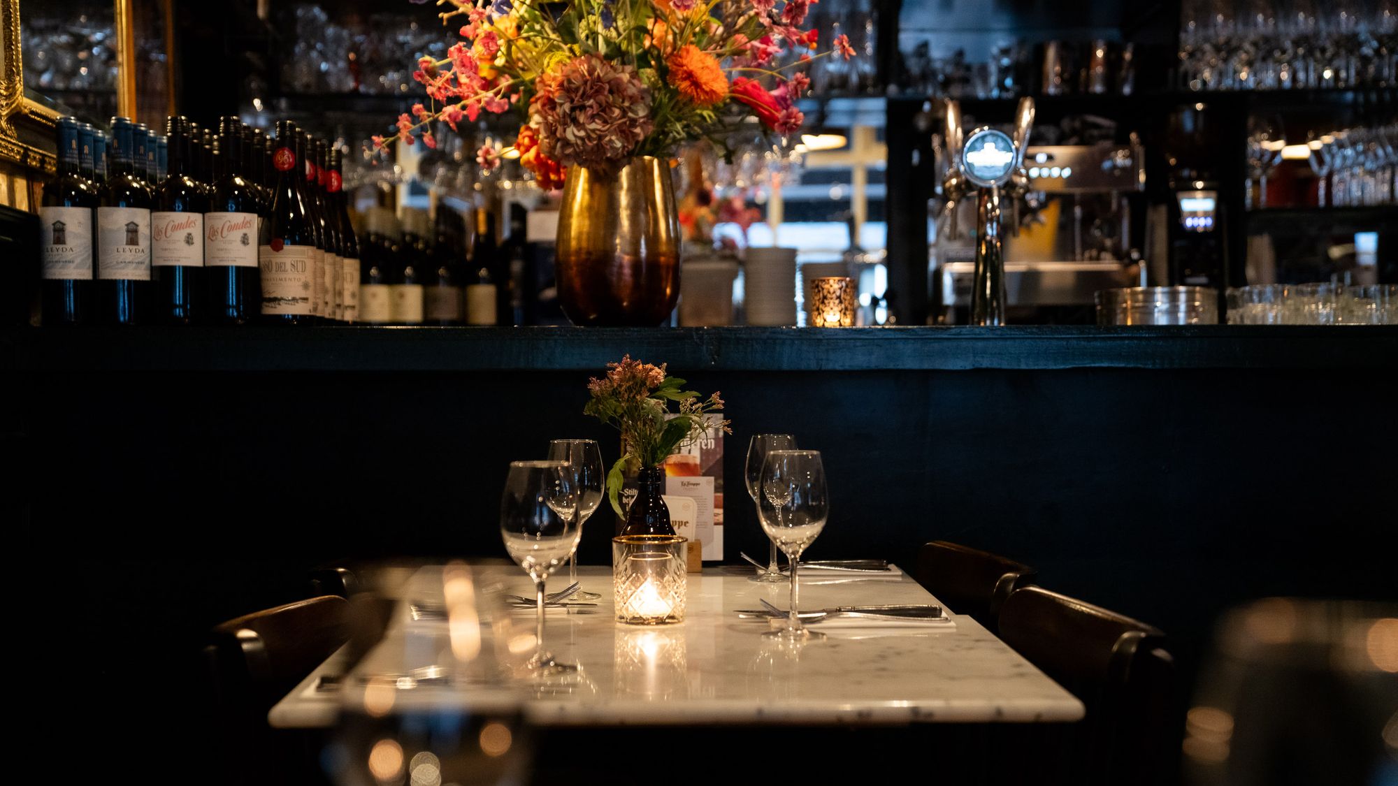 De bar met bloemen en een gedekte tafel bij kaarslicht