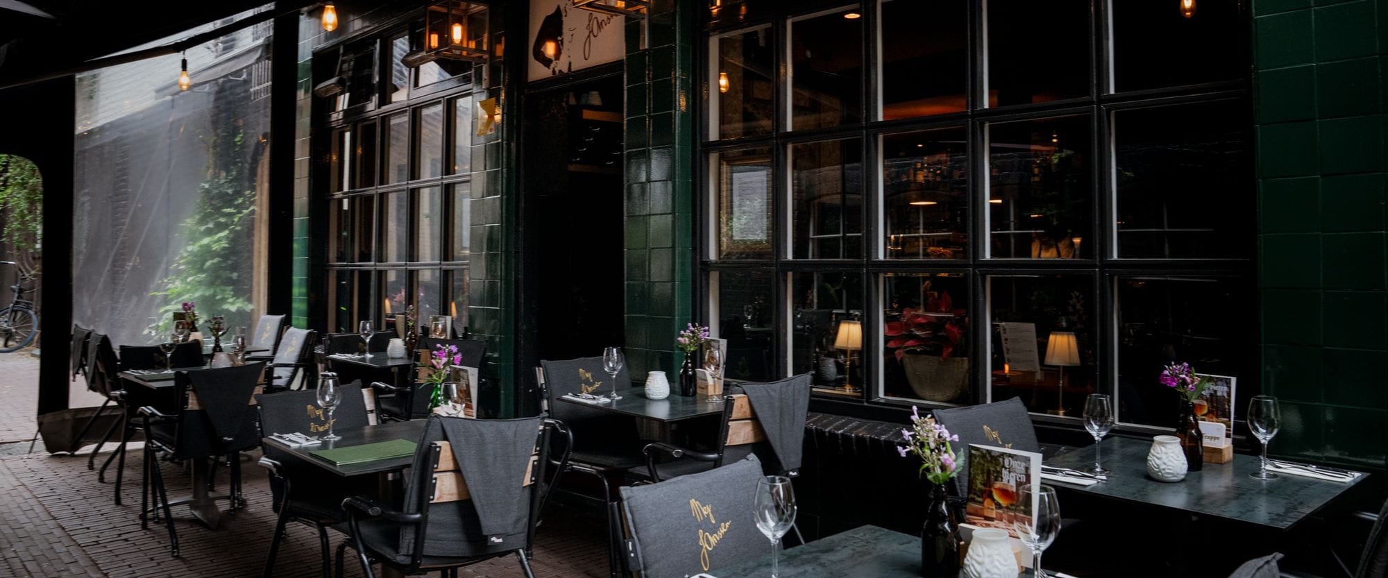 De serre aan de Duizelsteeg met gedekte tafels en groene menukaarten