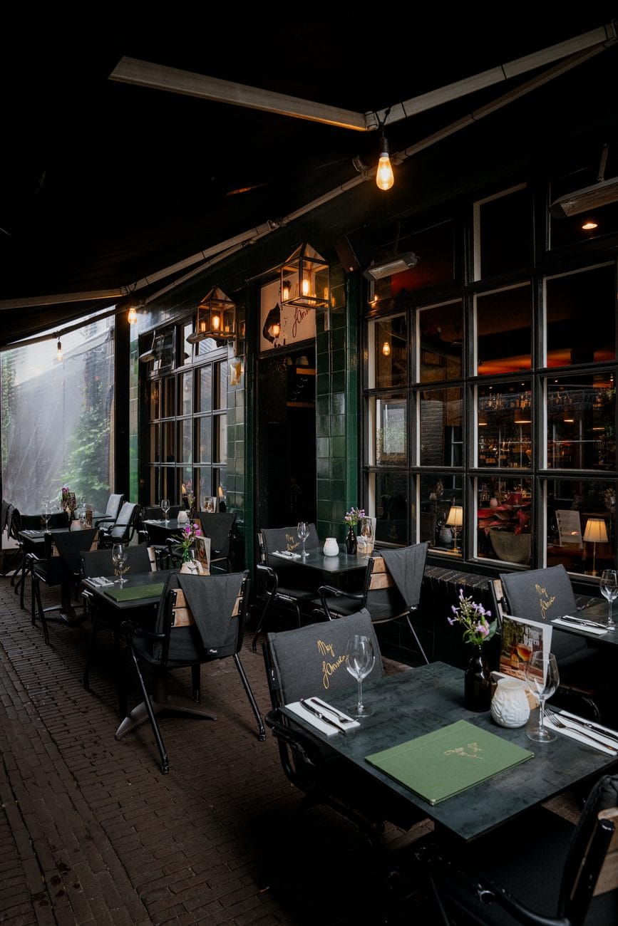 De zaal in de avond, met kaarslicht op de marmeren tafels