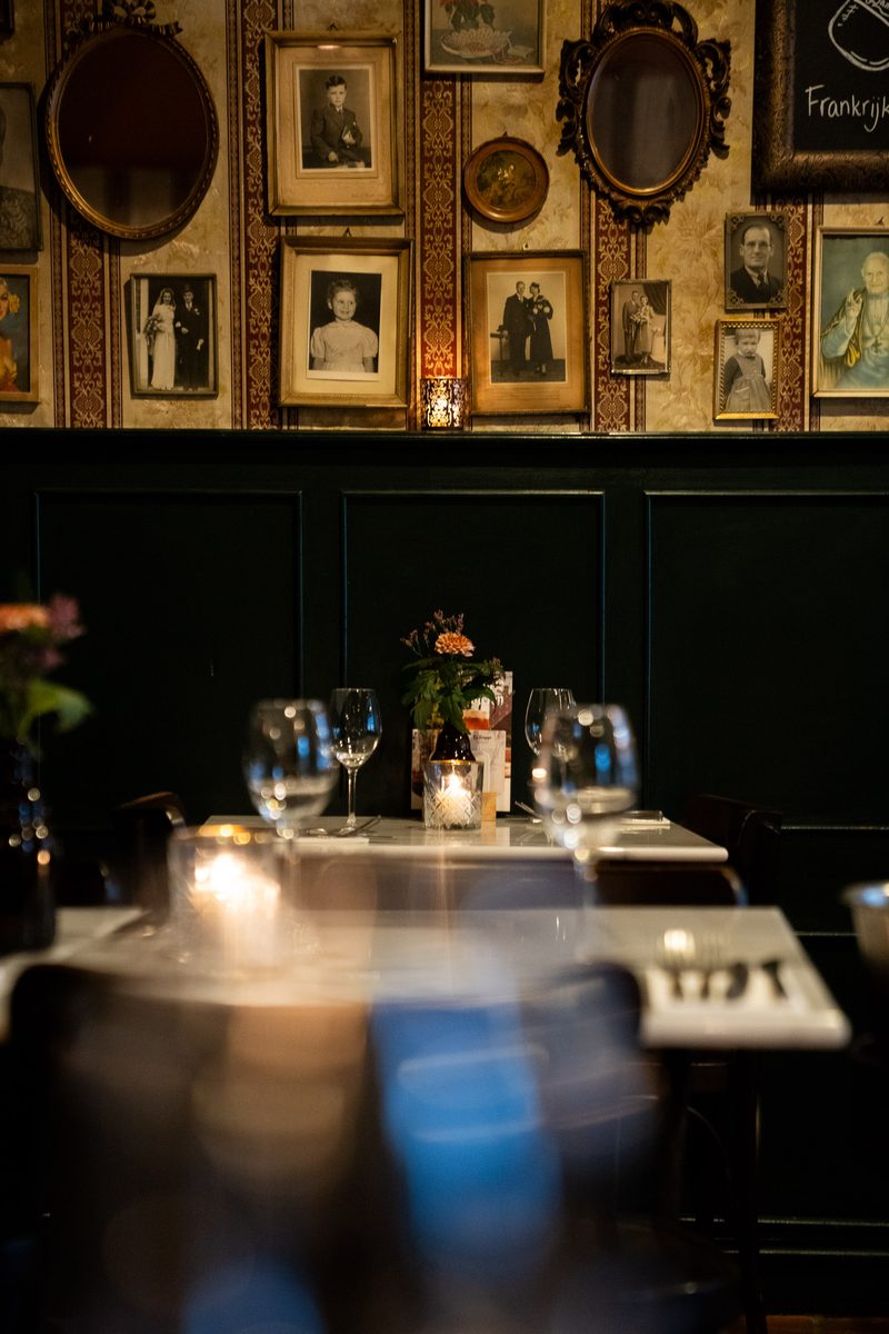 De muur vol ingelijste portretten boven een gedekte tafel
