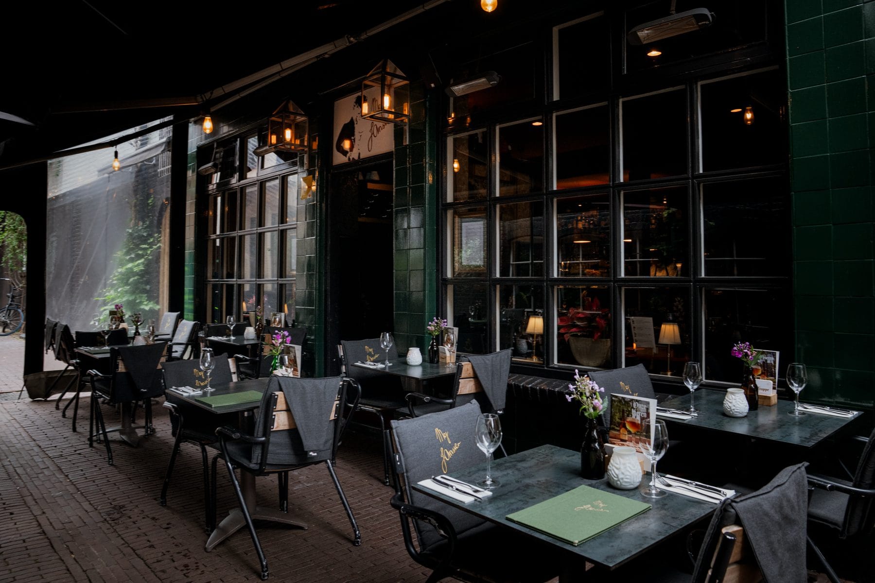 De serre met gedekte tafels en de groene menukaarten